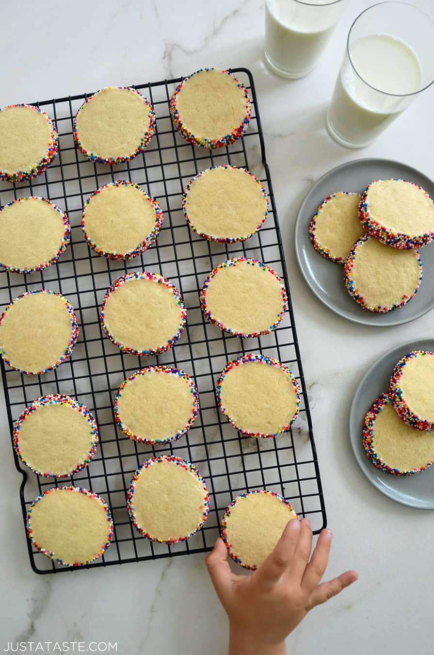 A child's hand reaching for Slice-and-Bake Butter Cookies on a wire cooling rack