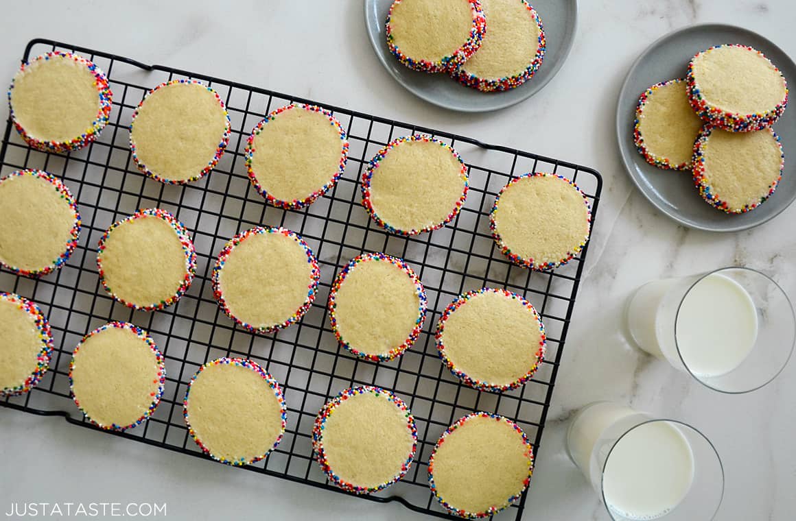 A top-down view of Slice-and-Bake Butter Cookies on a wire cooling rack next to two glasses of milk