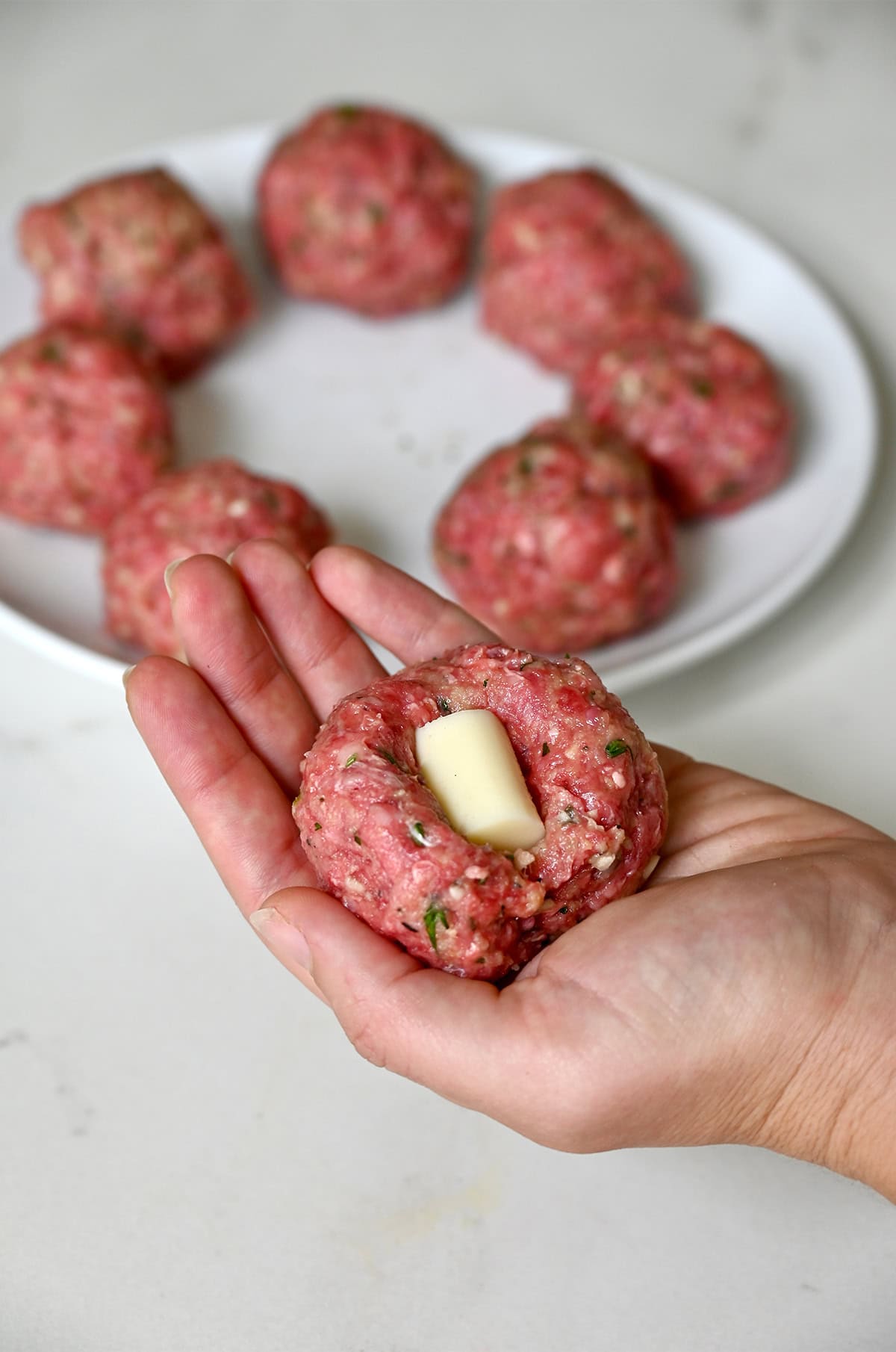 Stuffing a meatball mixture with mozzarella cheese.