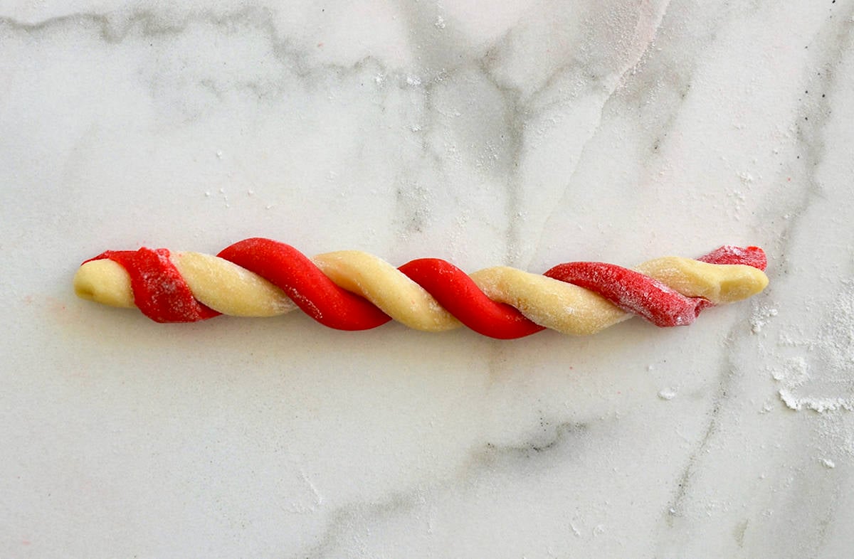 A red cookie dough log twisted together with plain cookie dough.