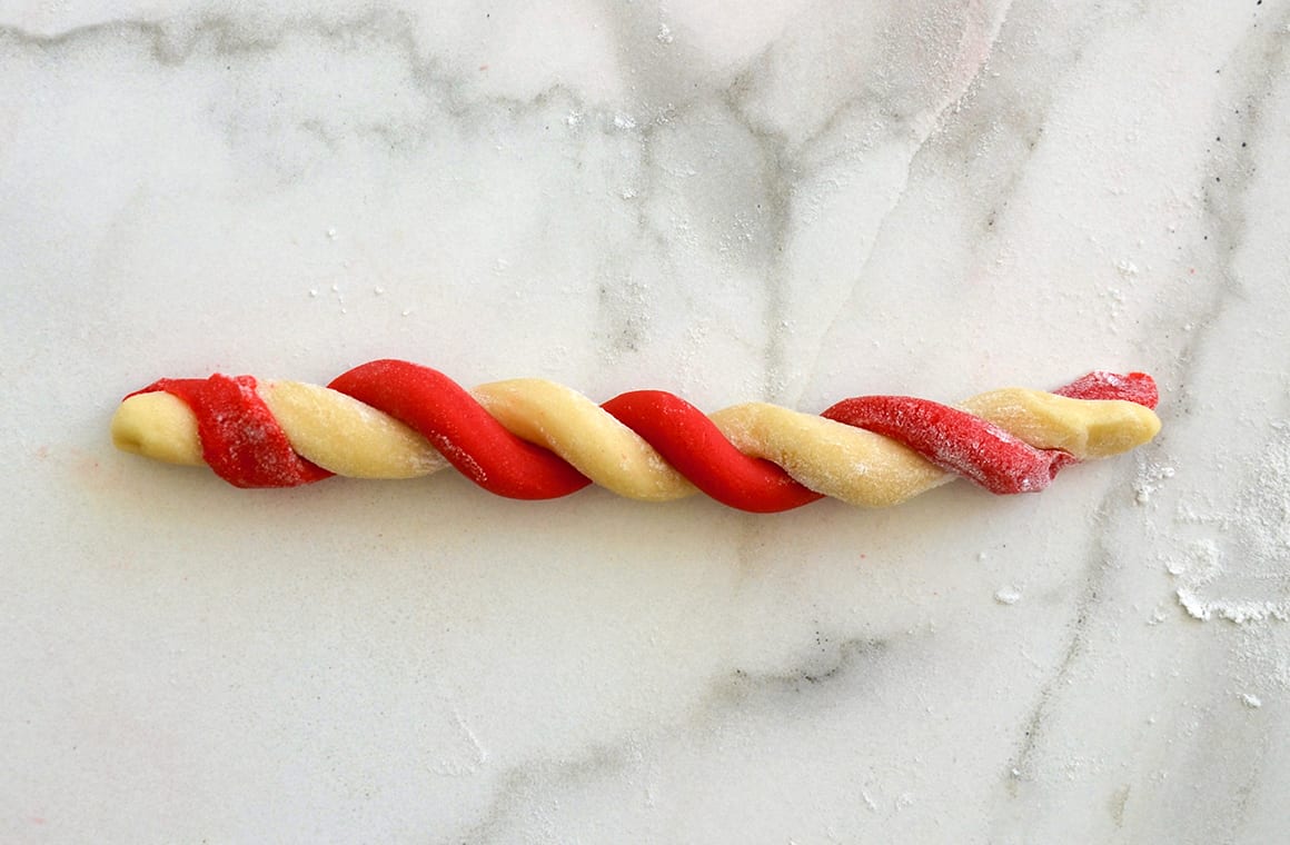 A red cookie dough log twisted together with plain cookie dough