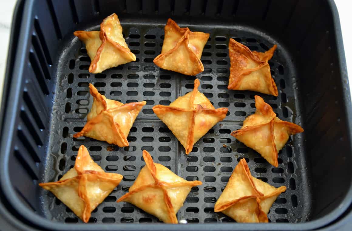 An air fryer basket containing crispy wontons