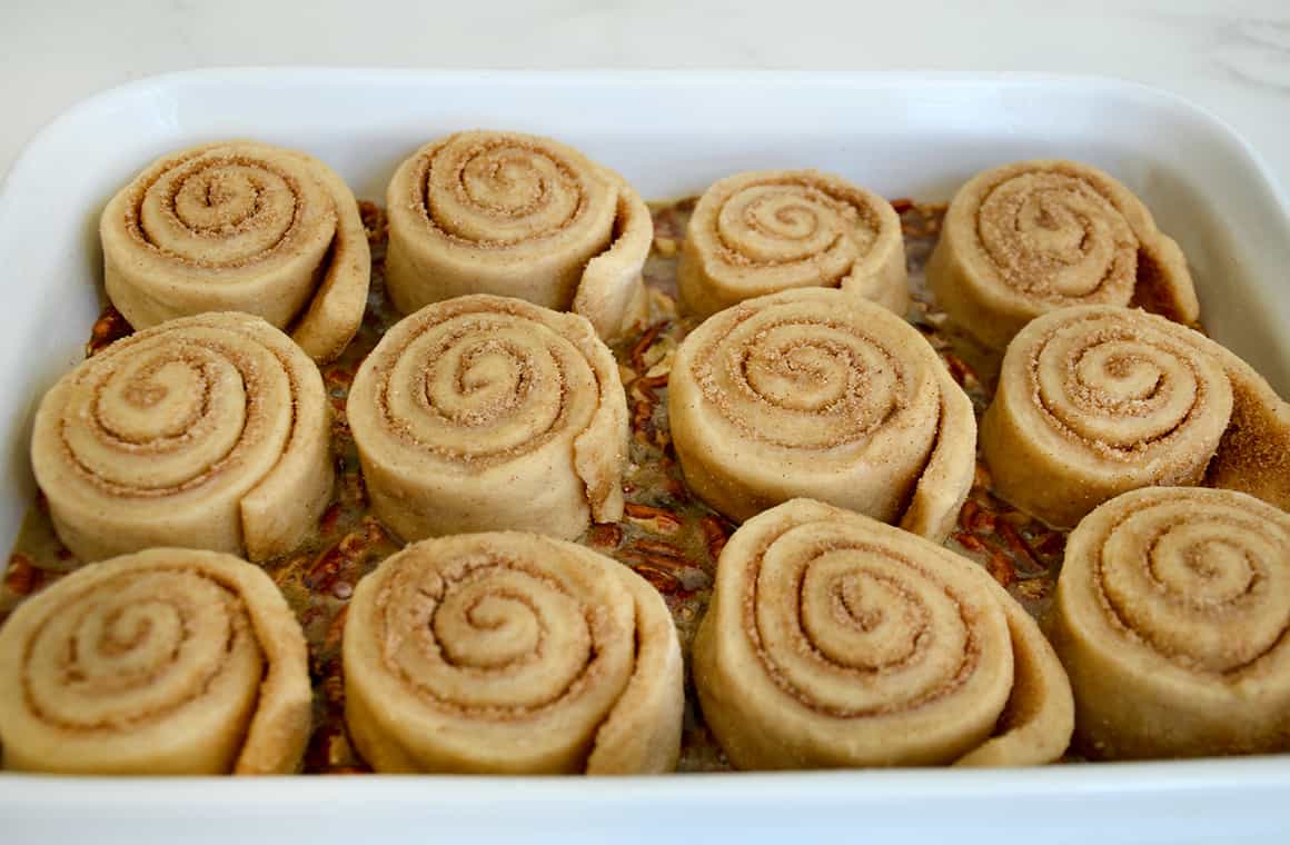 Unbaked caramel pecan buns in a white baking dish