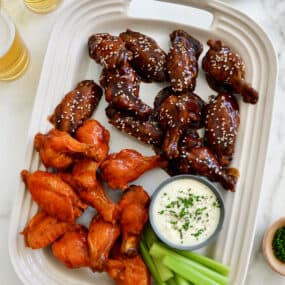 A large serving plate topped with Buffalo Air Fryer Chicken Wings and teriyaki Air Fryer Chicken Wings along with celery and ranch dipping sauce in a small ramekin