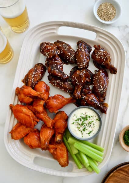 A large serving plate topped with Buffalo Air Fryer Chicken Wings and teriyaki Air Fryer Chicken Wings along with celery and ranch dipping sauce in a small ramekin