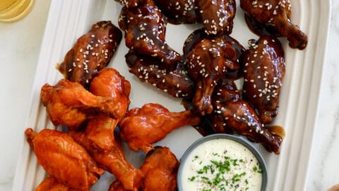 A large serving plate topped with Buffalo Air Fryer Chicken Wings and teriyaki Air Fryer Chicken Wings along with celery and ranch dipping sauce in a small ramekin
