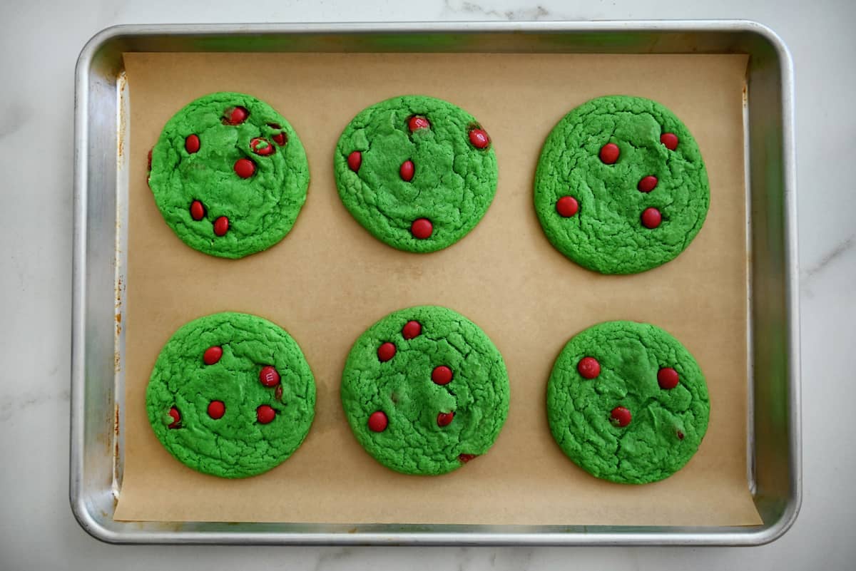 Baked Grinch cake mix cookies are on a parchment-lined baking sheet.