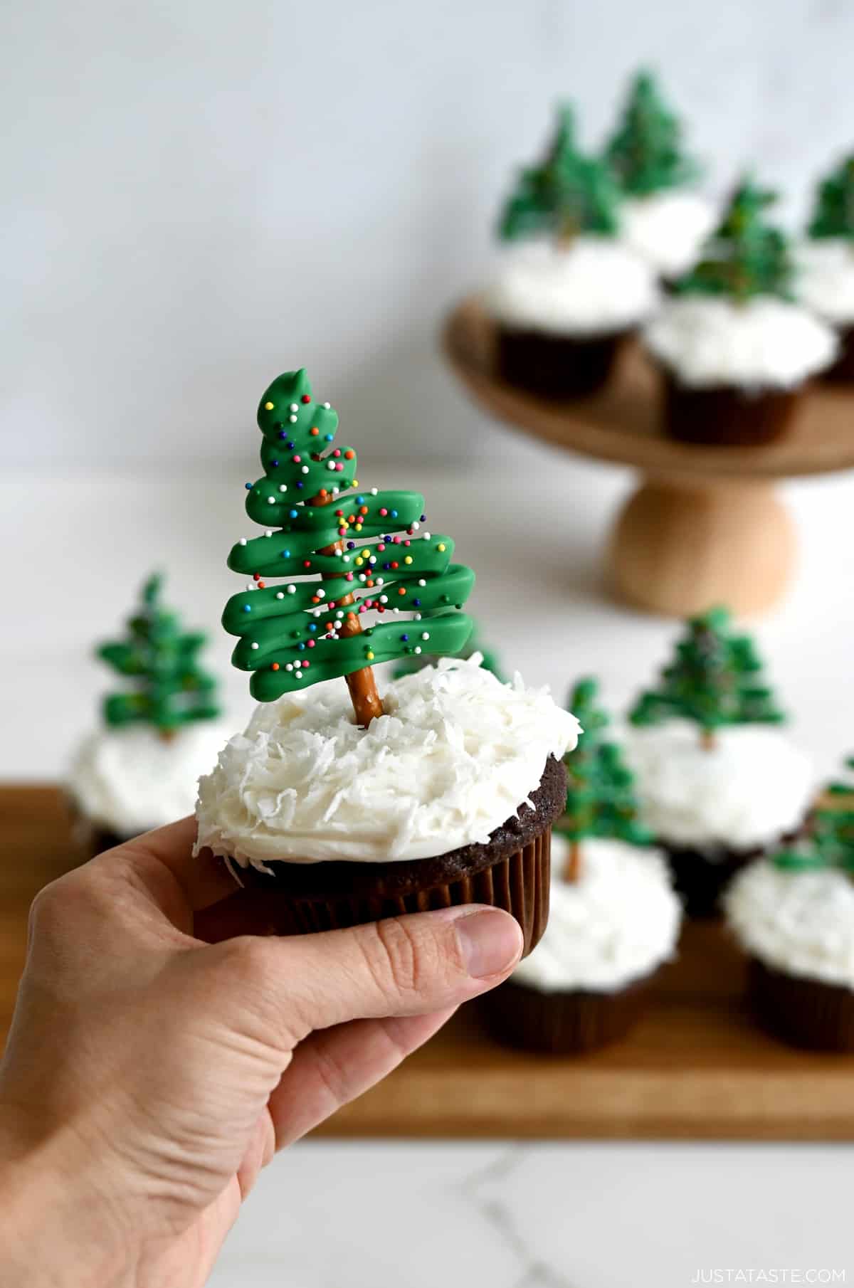 A hand holds a Chocolate Christmas Tree Cupcake.