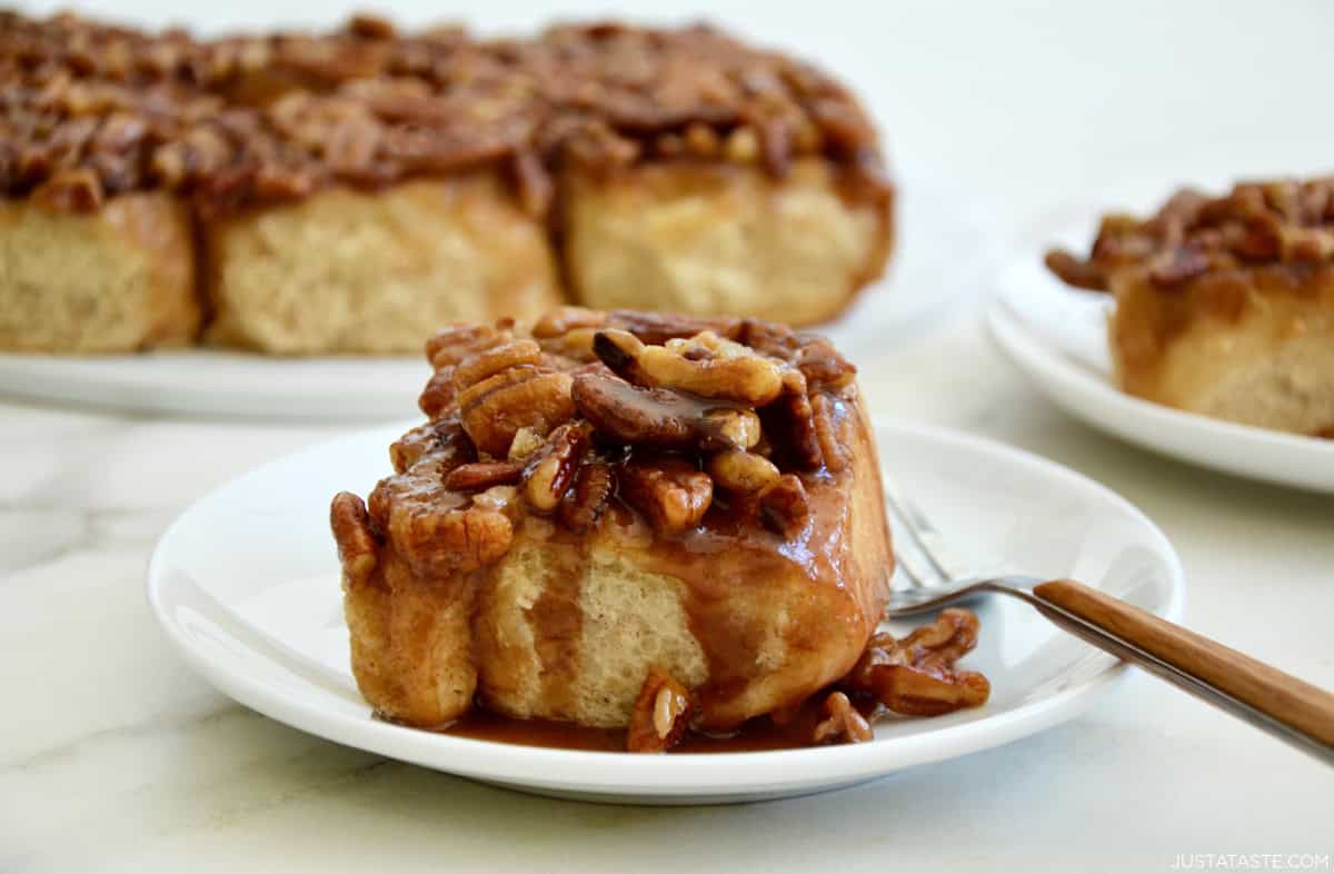 A freshly baked maple pecan sticky bun on a plate with a fork.