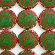 Rows of red and green-swirled Christmas Pinwheel Cookies studded with festive sprinkles
