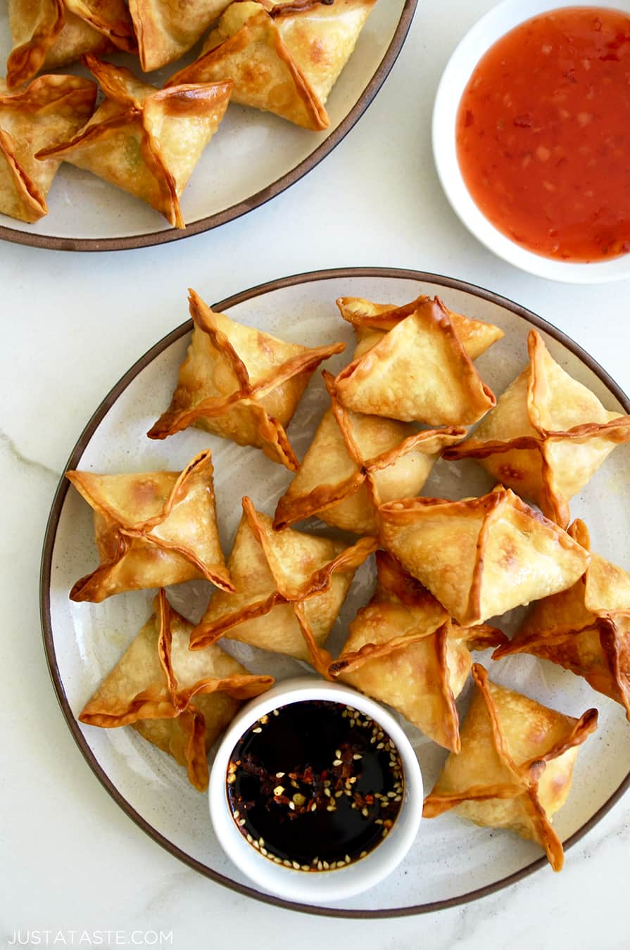 Air Fryer Cream Cheese Wontons on a plate with a small ramekin containing soy sauce next to a small bowl containing sweet chili sauce