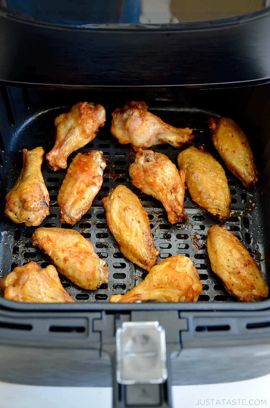 An air fryer basket containing crispy chicken wings