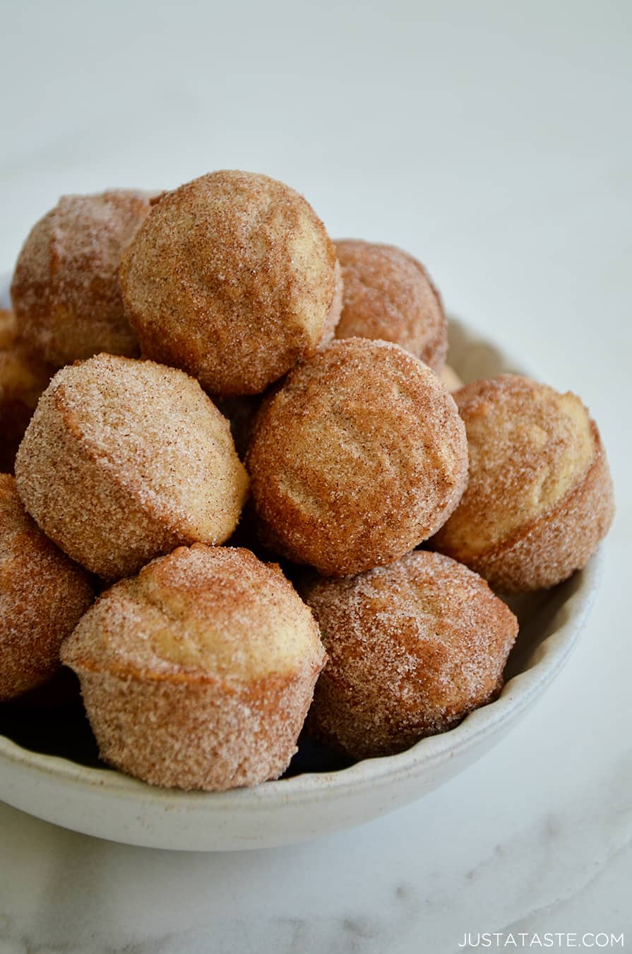 A white bowl piled high with Mini Sour Cream Doughnut Muffins