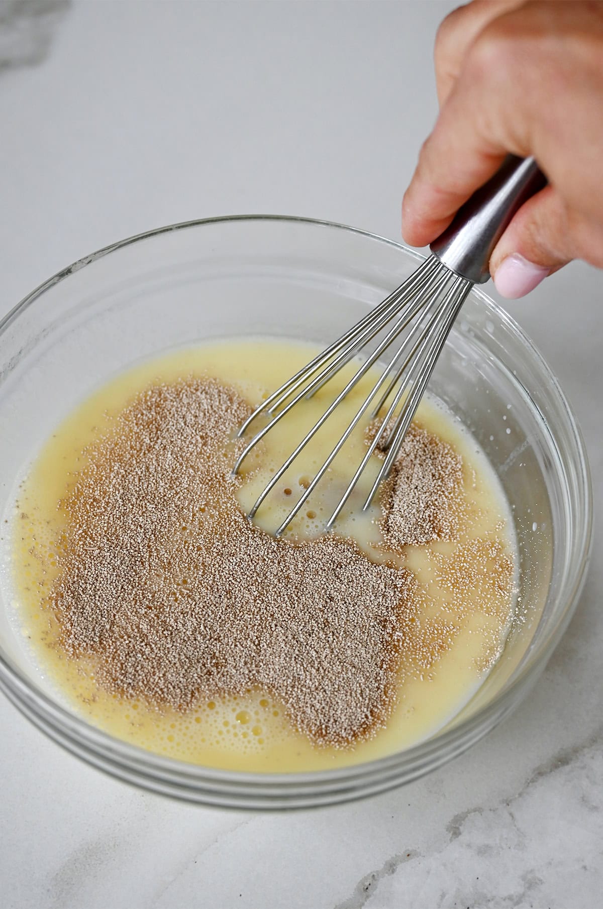 Mixing yeast with warm milk, butter and sugar to activate it.