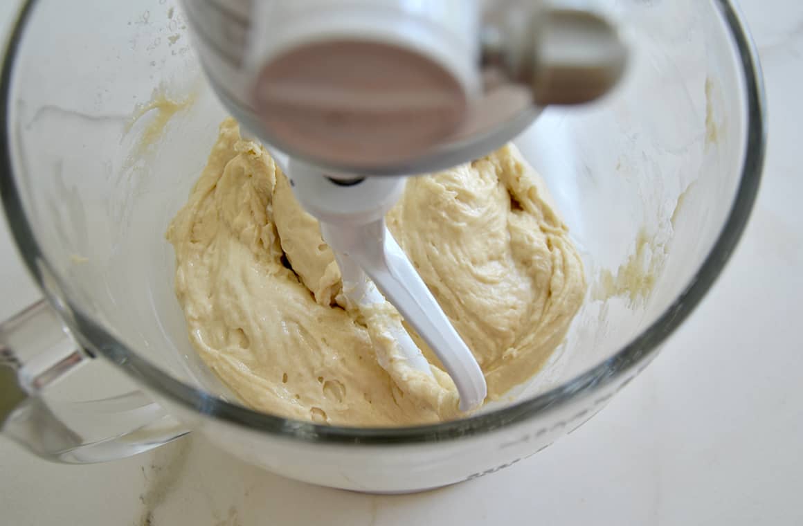 A large glass stand mixer bowl containing batter