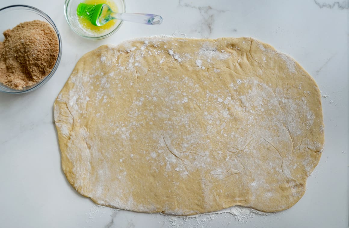 A top-down view of rolled out dough on a marble surface