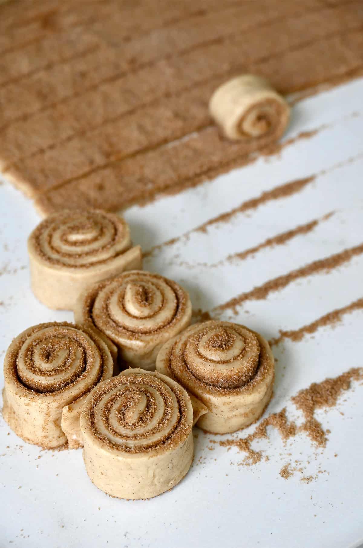 Rolling up strips of cinnamon sugar-filled dough to make sticky buns.
