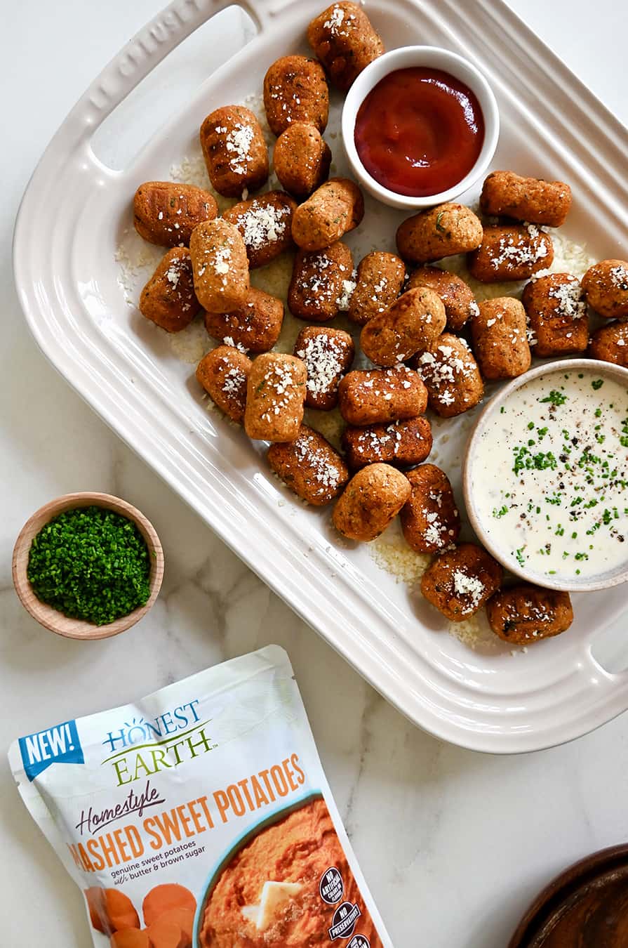 A platter of sweet potato tots with bowls of ketchup and Ranch