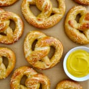 Golden brown soft pretzels next to a small dish containing yellow mustard above text that reads, "Easy Homemade Soft Pretzels"