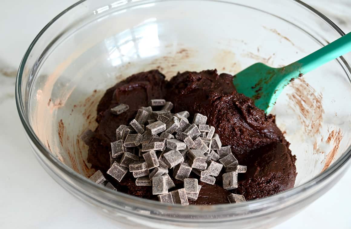 A clear bowl containing brownie batter and chocolate chunks