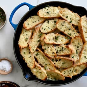 A top-down view of French Onion Chicken in a blue Le Creuset skillet