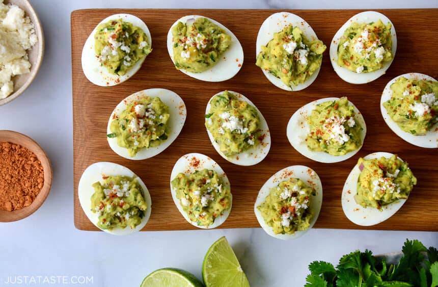 Deviled eggs on a platter surrounded by small bowls of cheese and seasoning