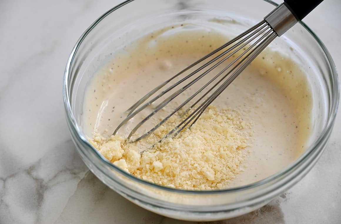 Homemade Caesar salad dressing in a glass bowl with a whisk