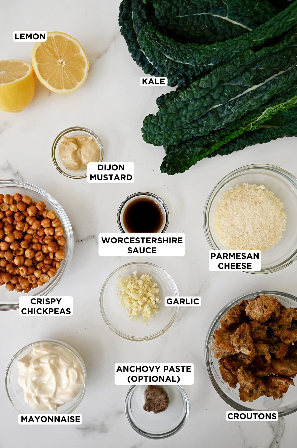 Kale Caesar salad ingredients in various sizes of glass bowls.