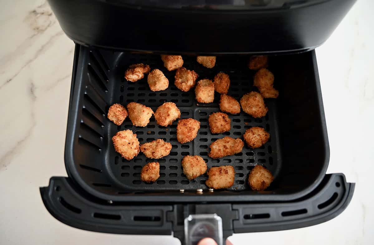 Golden brown and crispy chicken nuggets in an air fryer basket.