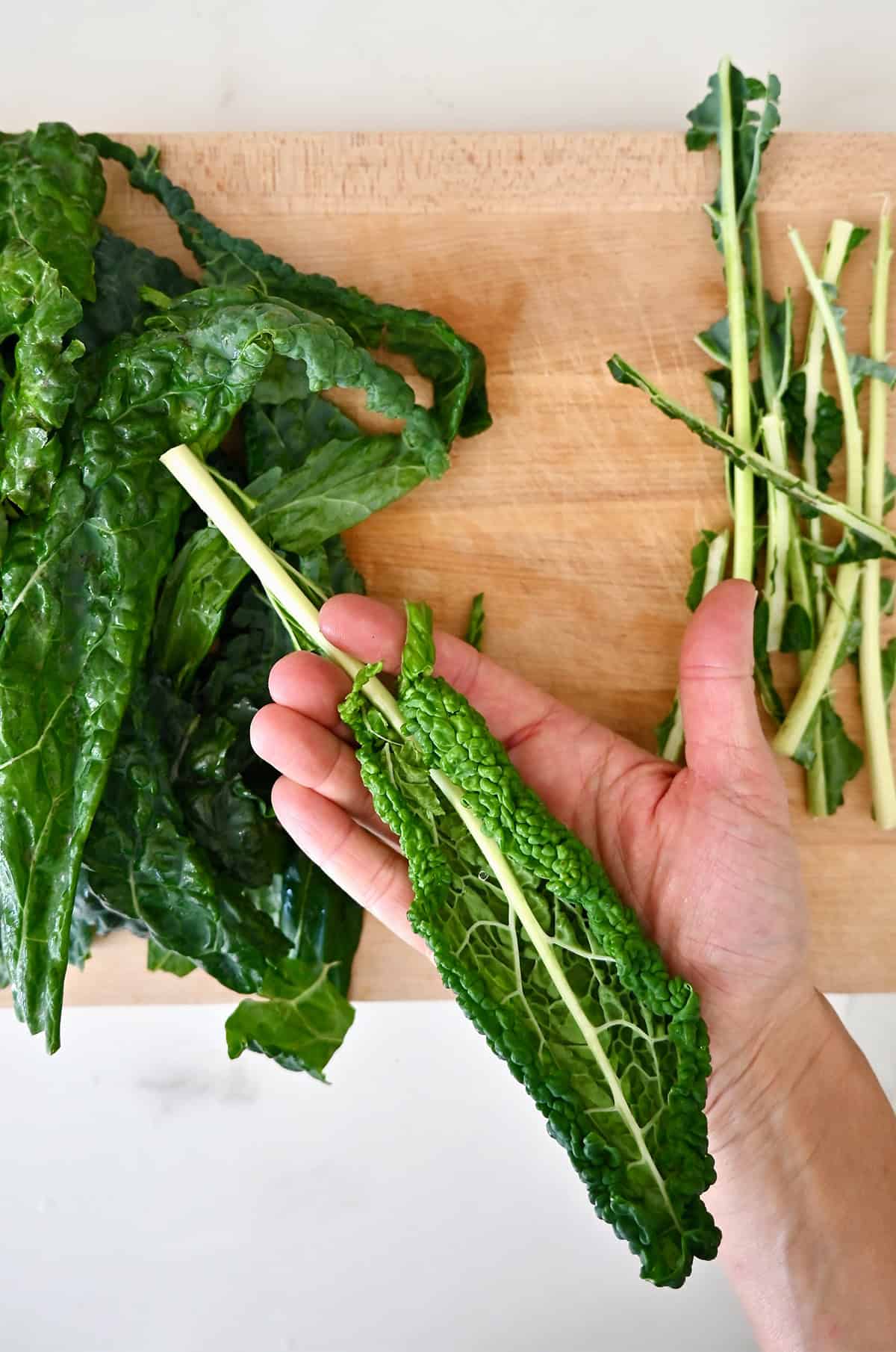 Showing how to de-stem kale by stripping the leaves off by hand.