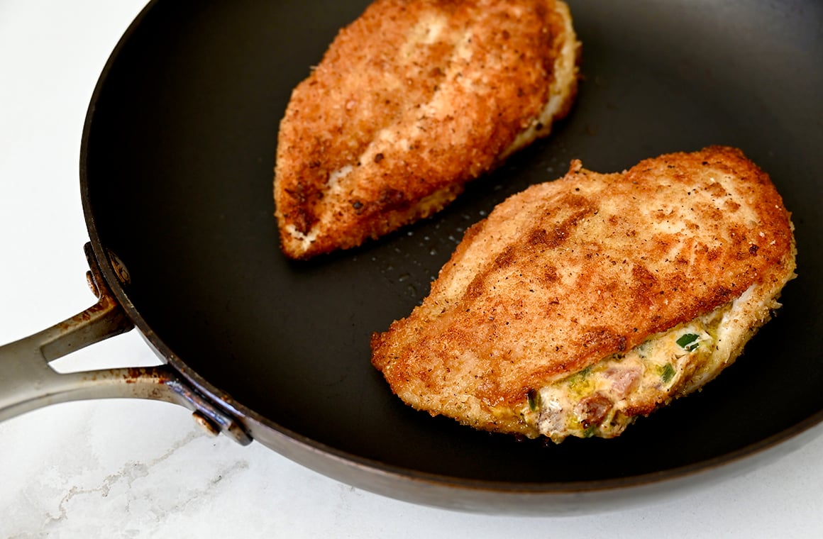 A skillet containing two stuffed chicken breasts 