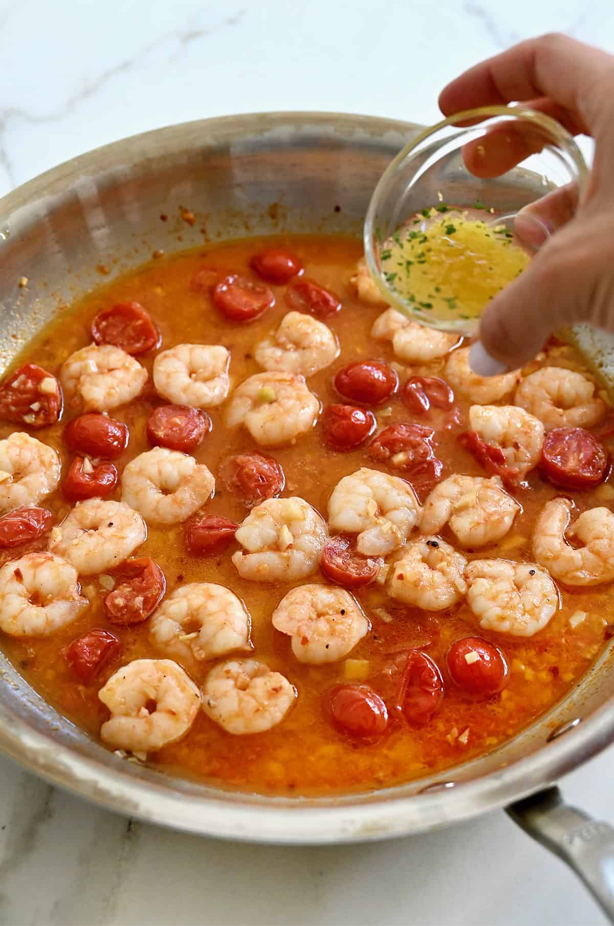 Adding fresh lemon juice to a pan with cooked shrimp and tomatoes.