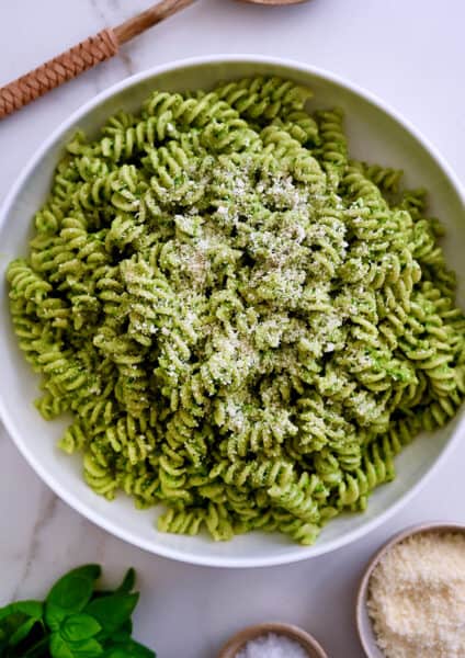 A large serving bowl containing Broccoli Pesto Pasta garnished with parmesan cheese