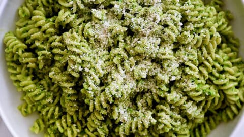 A large serving bowl containing Broccoli Pesto Pasta garnished with parmesan cheese