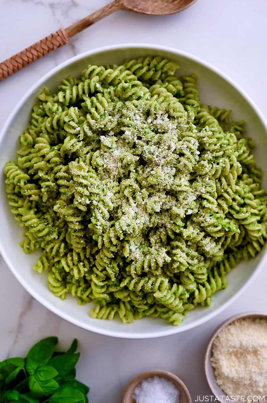 A large serving bowl containing Broccoli Pesto Pasta garnished with parmesan cheese