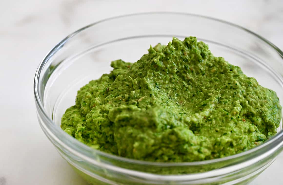 A clear bowl containing broccoli pesto