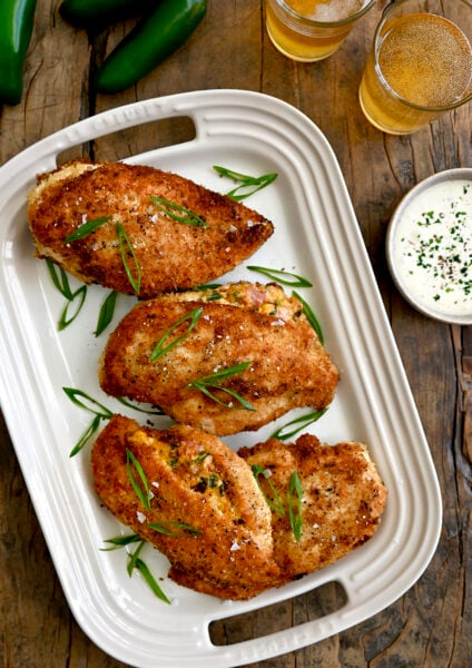A white platter containing Stuffed Jalapeno Popper Chicken breasts with scallions