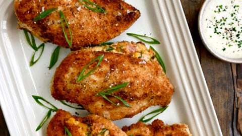 A white platter containing Stuffed Jalapeno Popper Chicken breasts with scallions