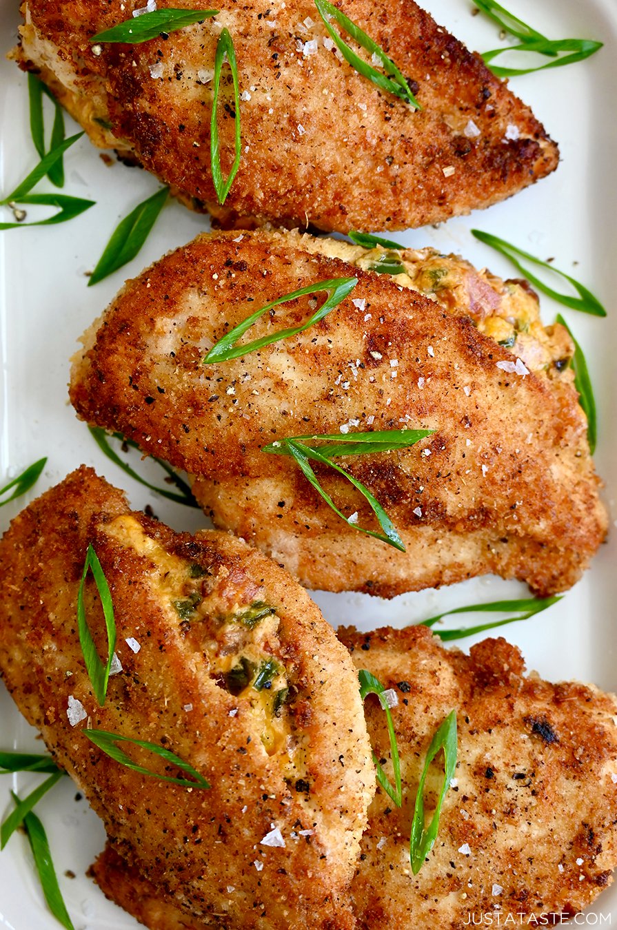 A close-up of stuffed chicken breasts on a white platter topped with sliced scallions