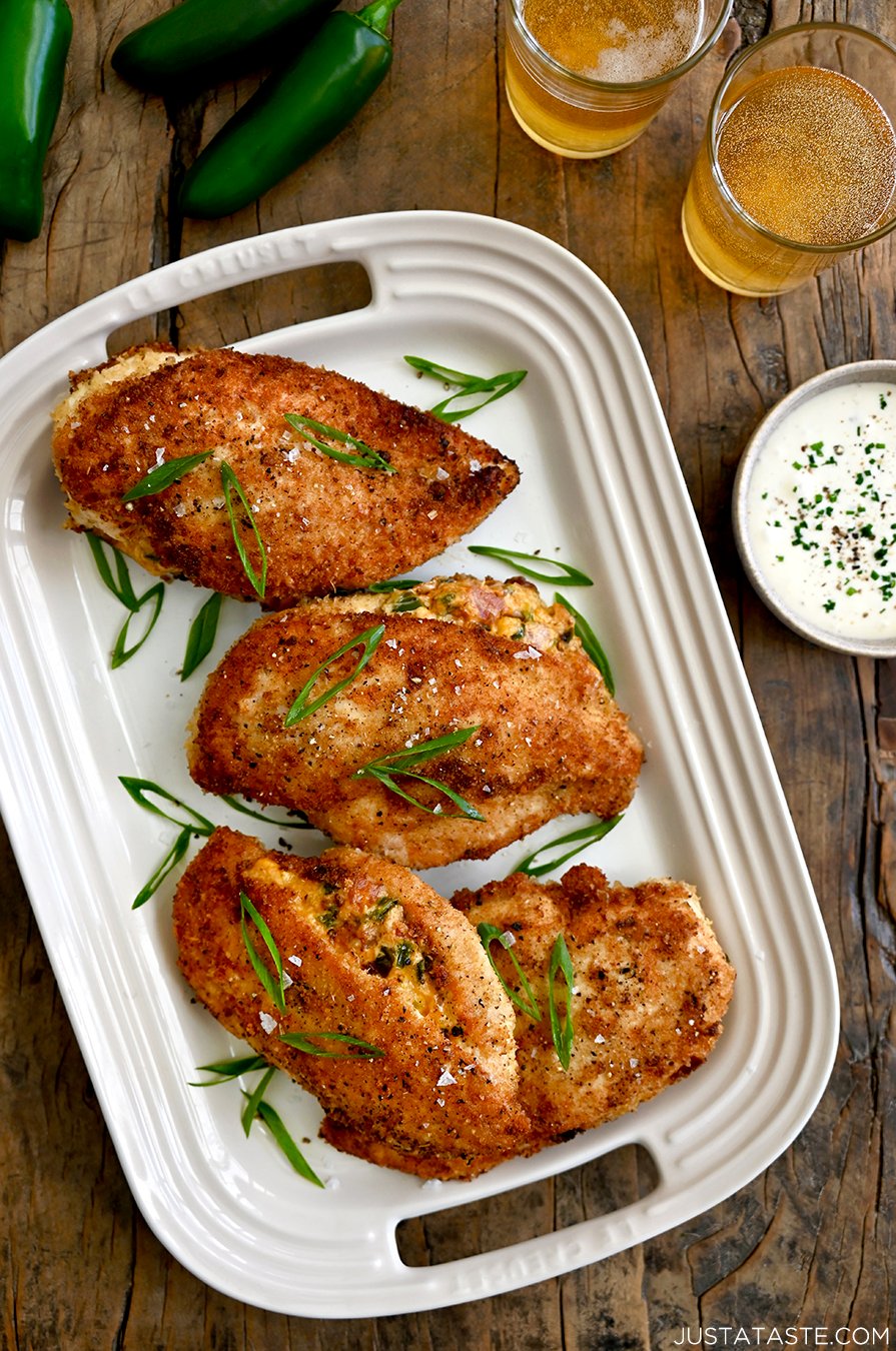 A white platter containing Stuffed Jalapeno Popper Chicken breasts with scallions