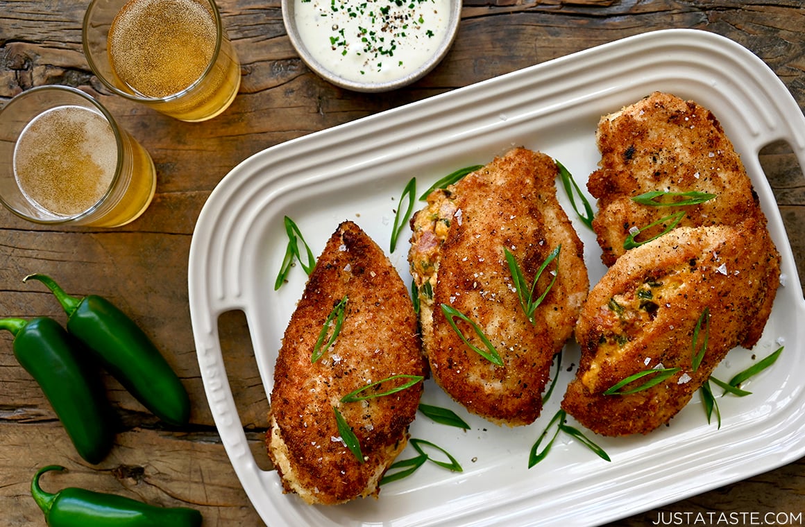 A white platter with chicken breasts surrounded by small bowls and drinking glasses