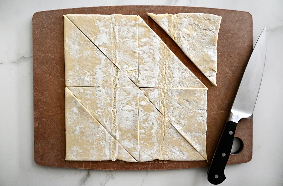 Store-bought puff pastry on a wood cutting board with a sharp knife