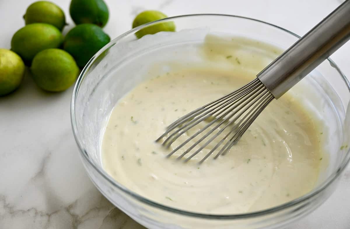 Three-ingredient key lime pie filling in a bowl with a whisk.