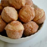 Mini sour cream doughnut muffins with cinnamon sugar piled high in a bowl.
