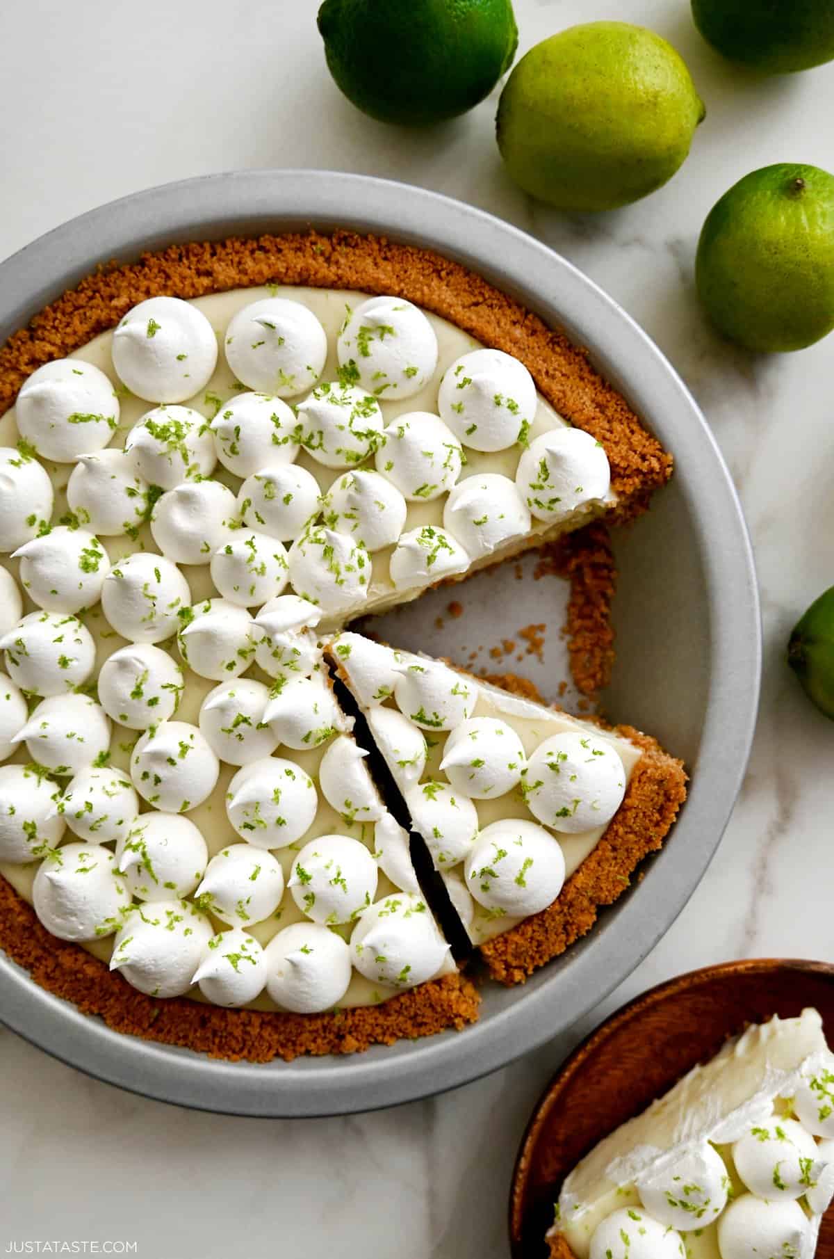 Key lime pie with a homemade graham cracker crust topped with dollops of whipped cream and zest of a lime.