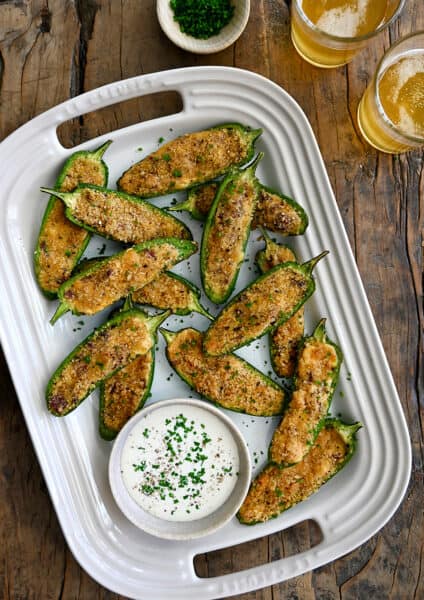A top-down view of Air Fryer Jalapeno Poppers on a white serving plate next to a small bowl filled with Ranch dressing