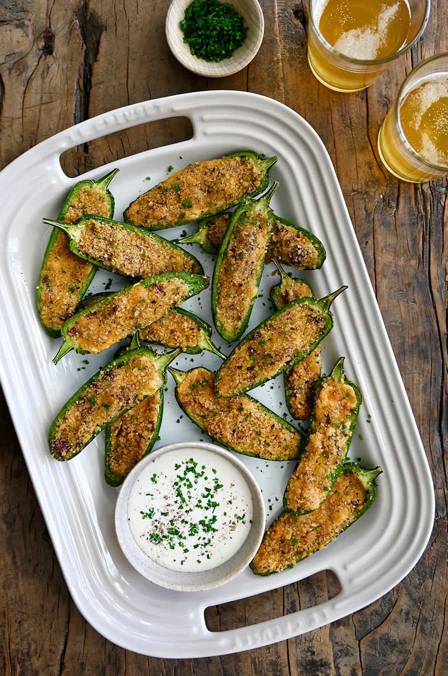 A top-down view of Air Fryer Jalapeno Poppers on a white serving plate next to a small bowl filled with Ranch dressing