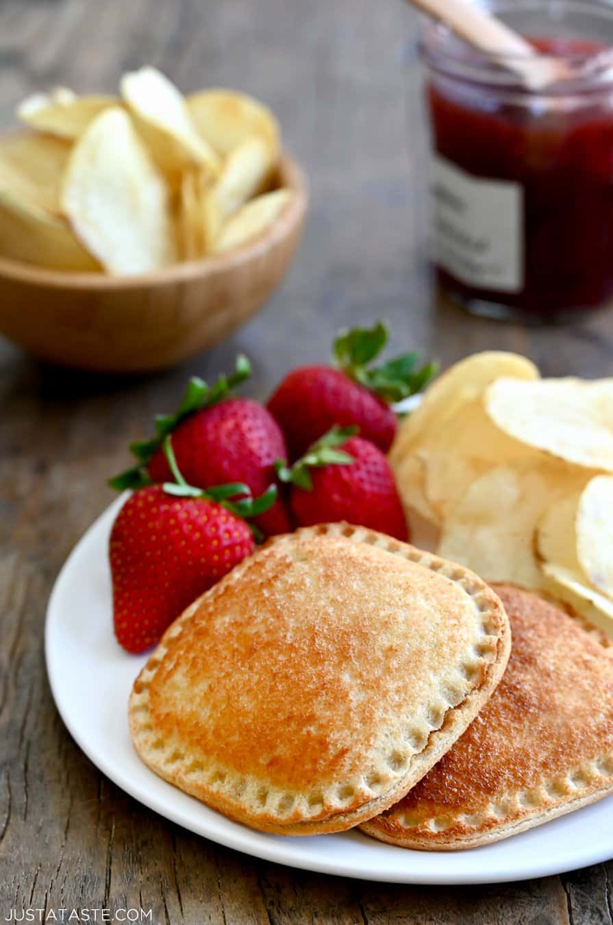 Air Fryer Peanut Butter and Jelly Uncrustables on a white plate with strawberries and potato chips