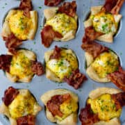 A top-down view of Bacon, Egg and Cheese Toast Cups in a muffin pan.