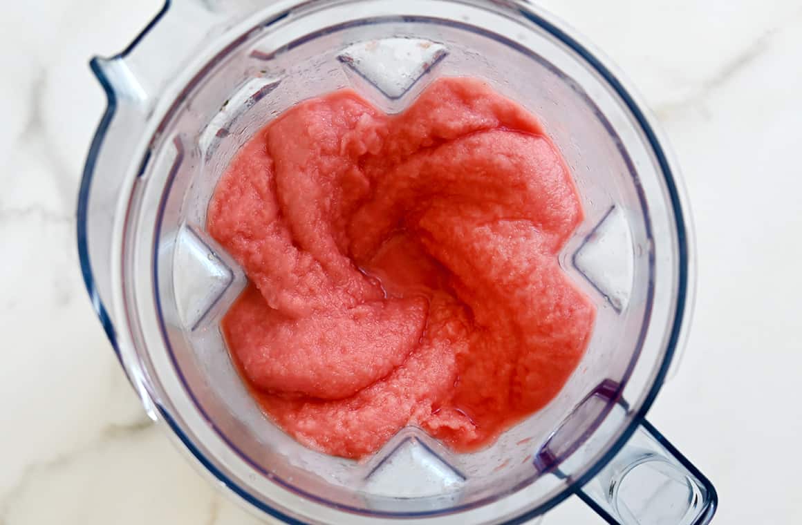 A top-down view of a frozen blended drink in a blender pitcher